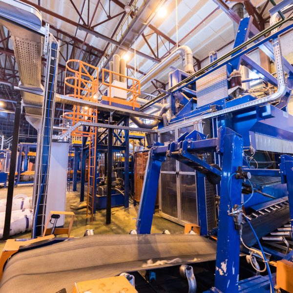 Modern operational plant equipment producing fiberglass with rolls of rock wool or glass wool on the background heavy industry machinery metalworking workshop concept.